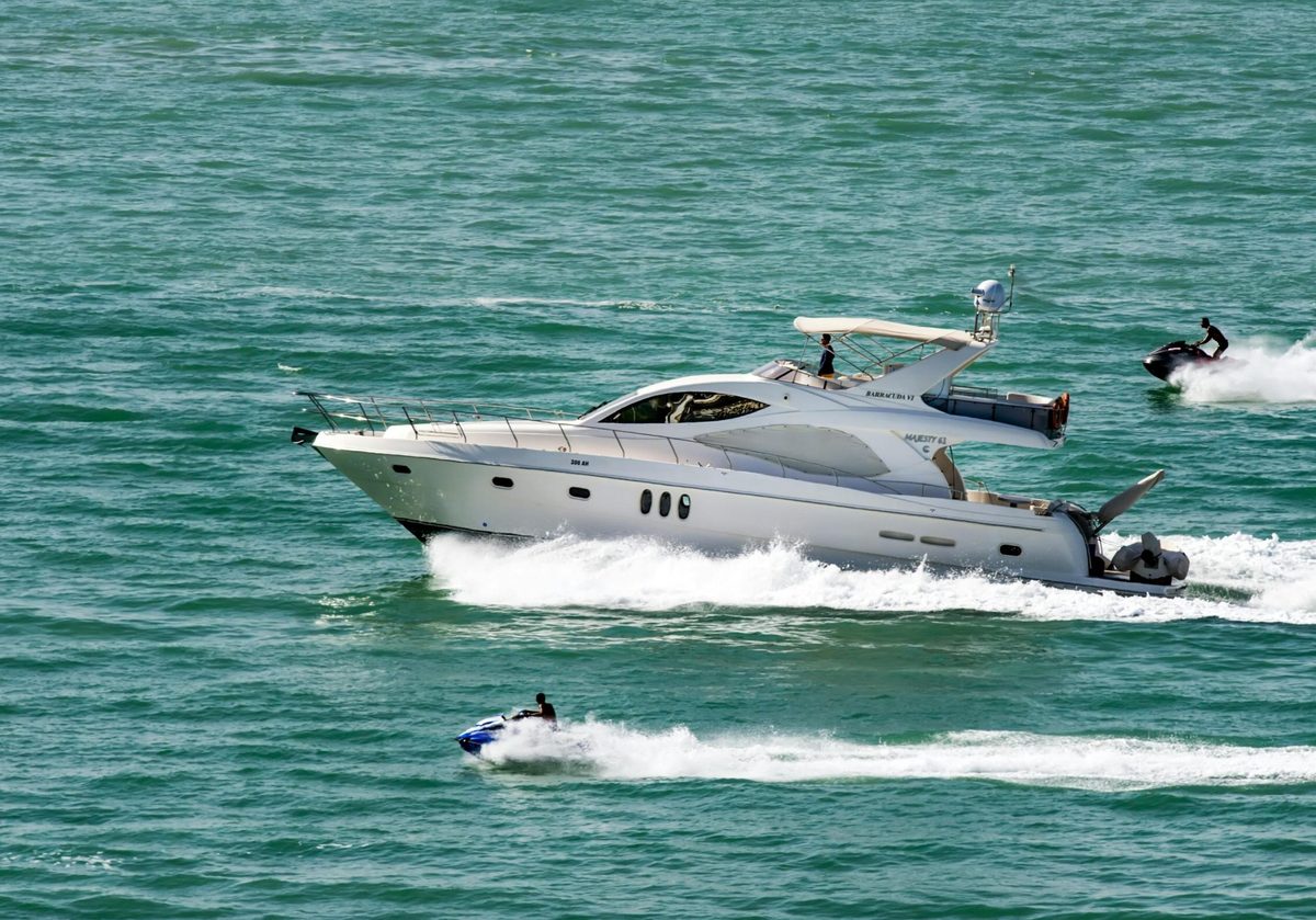 A yacht and jet skis on bright turquoise water